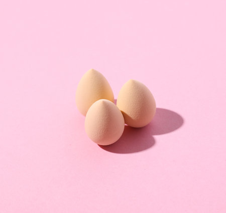 Eggs makeup sponges blender on pink background. Creative layout. Minimalism creative beauty still...