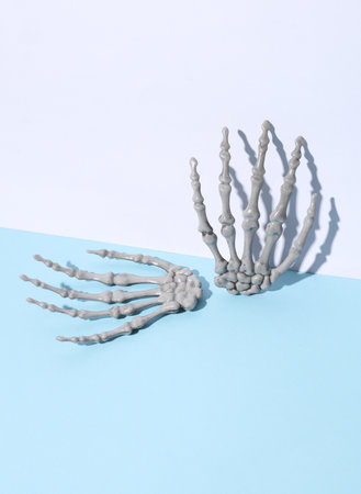 Plastic skeleton hands on blue white background. Minimalism halloween still lifeの写真素材