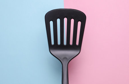 Black kitchen spatula on pink blue backgroundの写真素材