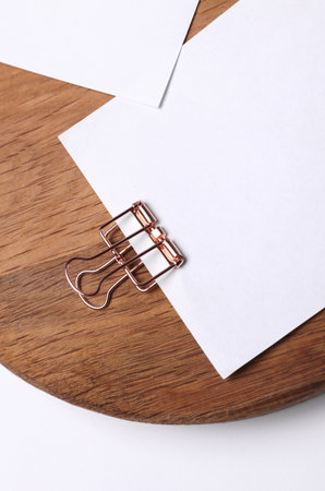 Memo white square sheets of paper with binder clips on round wooden board