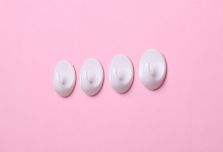White plastic hanger hooks on pink backgroundの写真素材
