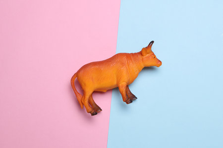 Toy plastic bull on pink blue backgroundの写真素材