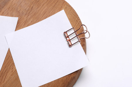 Memo white square sheets of paper with binder clips on round wooden boardの写真素材
