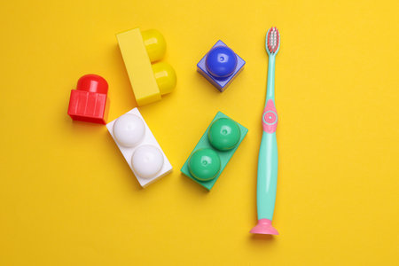 Children's plastic toothbrush with toy bricks on yellow backgroundの写真素材