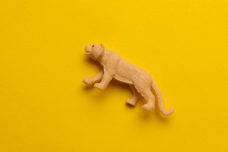 Plastic toy tiger figurine on yellow backgroundの写真素材