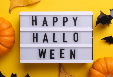 Happy Halloween letterboard text on LED Lightbox and decor, yellow background. Flat lay. Top viewの写真素材
