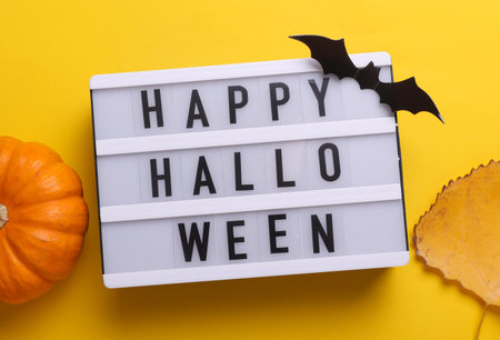 Happy Halloween letterboard text on LED Lightbox and decor, yellow background. Flat lay. Top viewの写真素材