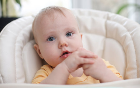 Cute little baby eats food from a plate at a table