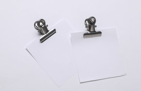 Memo white square sheets of paper with binder clips on white background. Stationery, education, business conceptの写真素材