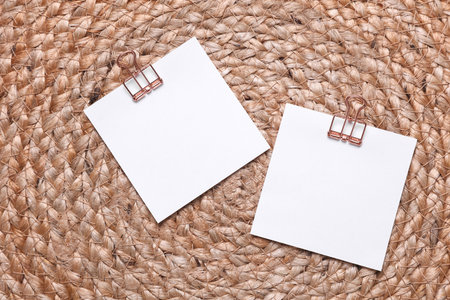 Memo white square sheets of paper with binder clips on straw mat. Stationery, education, business conceptの写真素材
