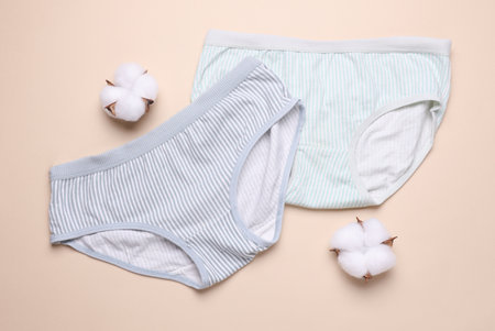 Women's comfortable panties with cotton flowers on beige background.