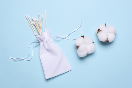 White bag with cotton swabs and cotton flowers on blue backgroundの写真素材
