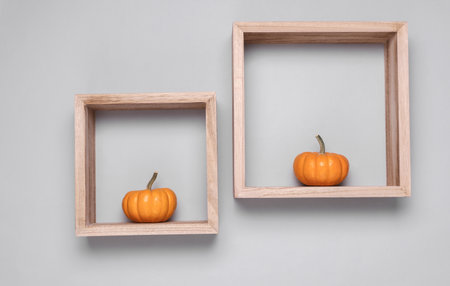 Miniature pumpkins in square wooden shelves on gray background