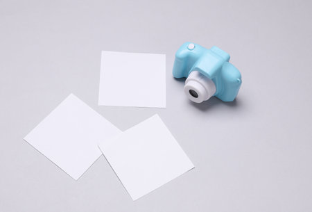 Toy plastic camera with blank cards on white background