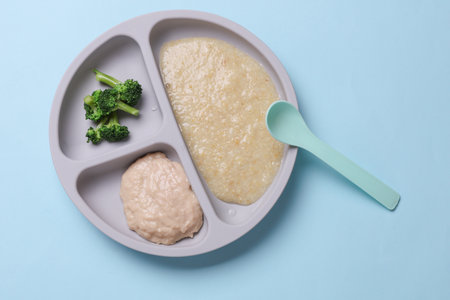 Baby food divider plate with healthy food on blue background