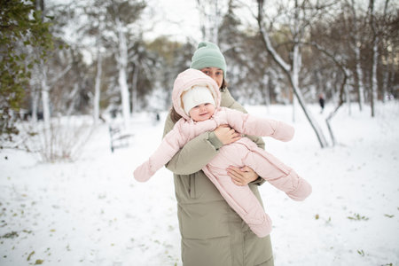 Mom walks with her little baby in her arms on a snowy winter dayの写真素材
