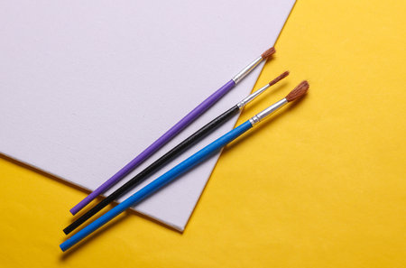 Set for drawing, children's creativity. White blank canvas and brushes on yellow background. Top...