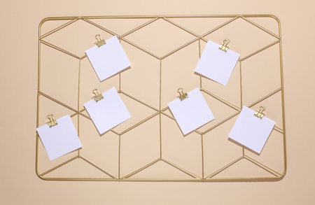 White square memo cards mockups attached to gold grid mood board on beige background. Top view