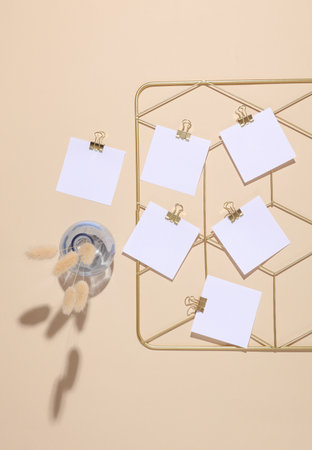White square memo cards mockups attached to gold grid mood board on beige background. Top view