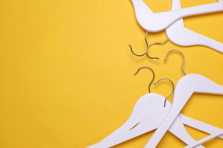 White wooden hangers on yellow background. Top view. Flat lay. Copy spaceの写真素材