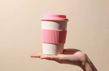 Eco plastic coffee cup in hand on beige background