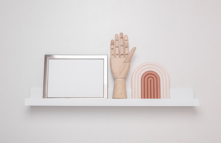 Shelf with white empty photo frames and decoration on white background. Mockup for design. Wall...