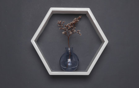 Hexagonal wall shelf and vase with lagurus flower on dark gray backgroundの写真素材