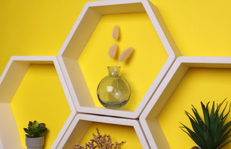 Hexagonal honeycomb wall shelves with decor on yellow backgroundの写真素材