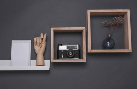 Shelf with white empty photo frame and decoration on dark gray background. Mockup for design. Wall...