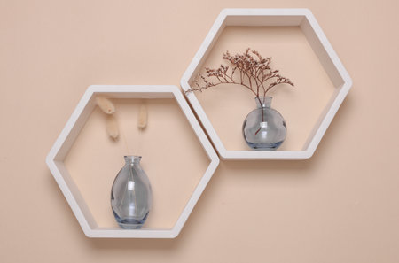 Hexagonal honeycomb shelves and vases with dry flowers on beige background. Wall decorの写真素材
