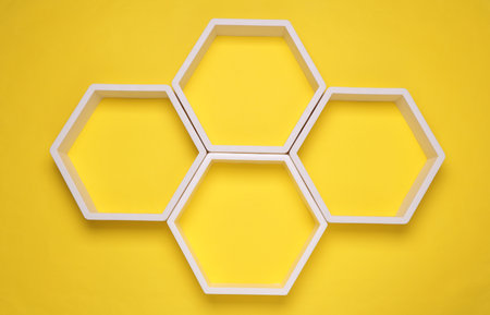 Hexagonal honeycomb wall shelves on yellow background