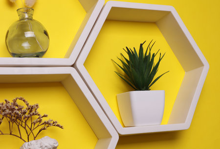 Hexagonal honeycomb wall shelves with decor on yellow backgroundの写真素材