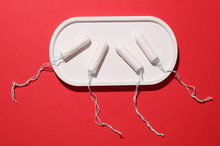 Tampons for feminine intimate hygiene in tray on red background. Menstruation, critical days, female...