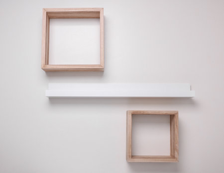 Square wooden and photo frame shelves on white wallの写真素材