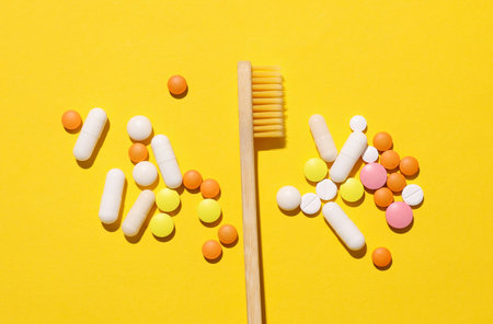 Toothbrush and pills on a yellow background