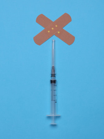 Medical Adhesive bandage plaster with syringe on blue backgroundの写真素材