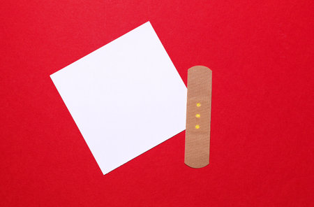 White business card with medical plaster on red background