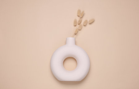 Autumn dry grass in Scandinavian plaster round vase on beige background. Top viewの写真素材