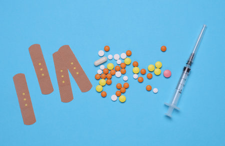 Many pills with Medical Adhesive bandage plasters, syringe on blue background