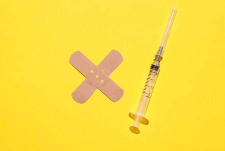Medical Adhesive bandage plaster with syringe on yellow backgroundの写真素材