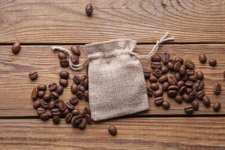 Coffee beans with miniature burlap bags on wooden tableの写真素材