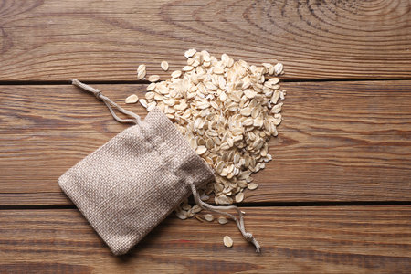 Dry oatmeal in miniature burlap bags on wooden table