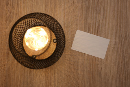 Loft lamp illuminates white blank business card on tableの写真素材