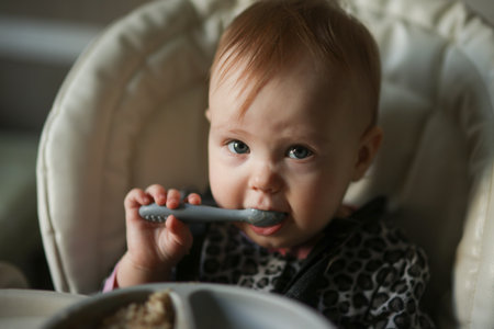 Cute baby eating on his own at the feeding table