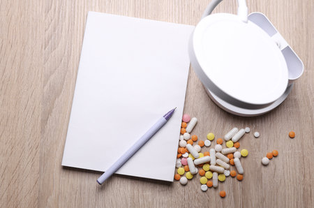 Blank medical journal or notebook with white cover and medicines on table. Mockup for designの写真素材