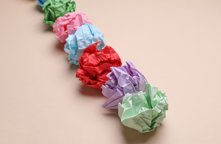 Colored balls of crumpled paper on a beige background.