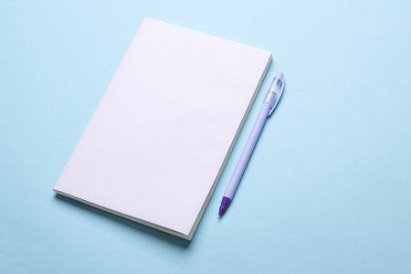 Magazine, sketchbook or notebook with white blank cover on blue background. Mockup for design