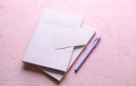 Magazines, sketchbooks or notebooks with white blank covers, business card on pink background....