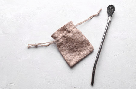 Miniature burlap bag and bombilla on a white concrete background