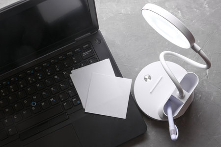 Desk LED lamp illuminates laptop keyboard with blank white memo cards